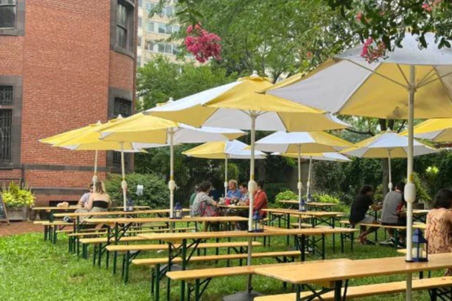 Tables with yellow umbrellas in an outside garden with beer and people taking