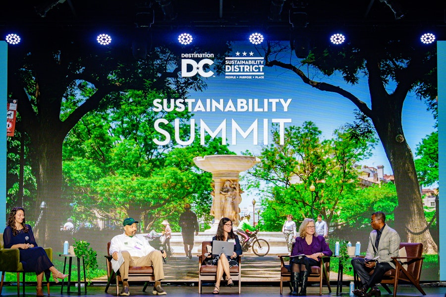 Panelists discuss sustainability initiatives against a vibrant backdrop of greenery and urban life at the Sustainability Summit.
