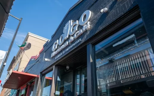 The entrance to the Go-Go Museum & Café features bold signage on a black-painted brick building under a bright blue sky.

