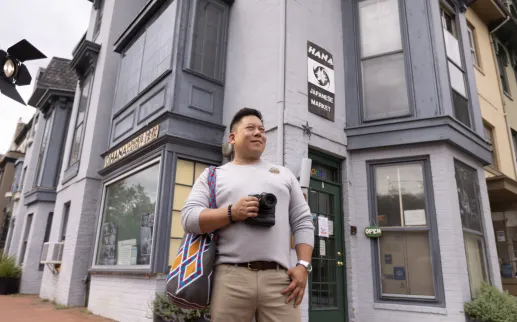 A visitor with a camera stands outside Ohana Japanese Market in Washington, DC.
